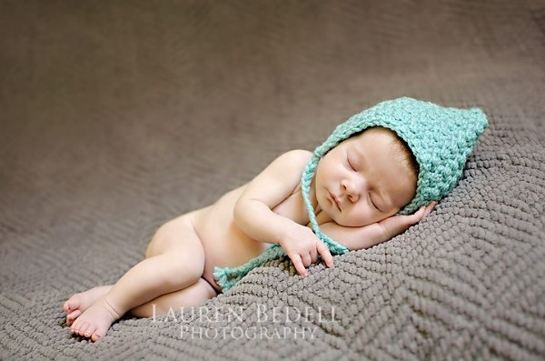A newborn baby wearing a blue crochet pixie bonnet.