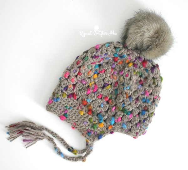 Acrochet bonnet with brightly coloured flecks and a fur pompom.