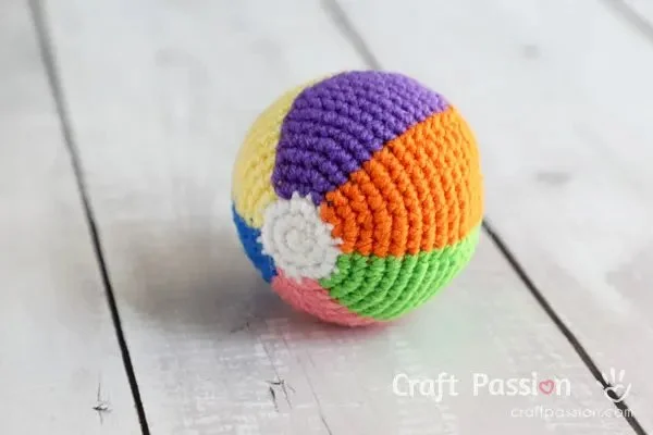 A mini crochet beach ball made in rainbow colours.