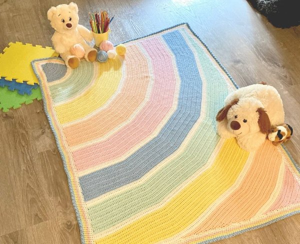 A crochet rainbow baby blanket isn soft pastel colours.