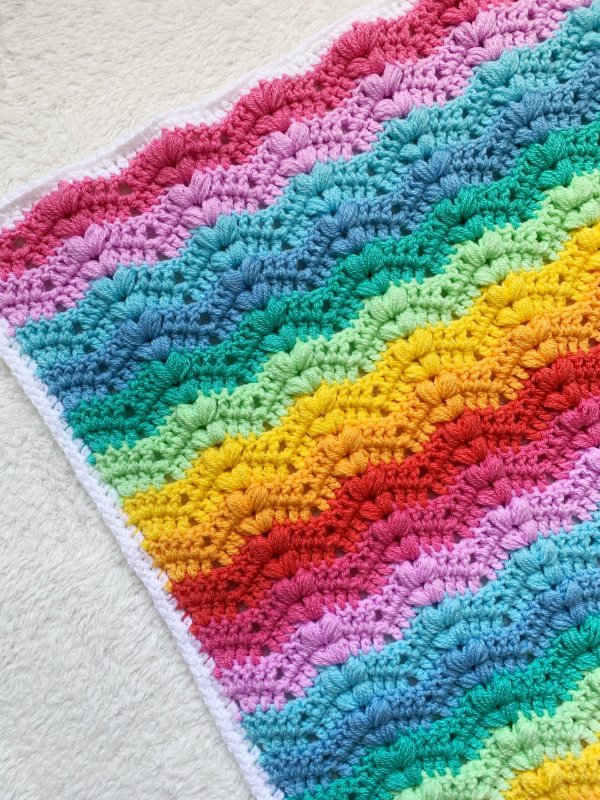 A crochet ripple baby blanket in bright rainbow colours.