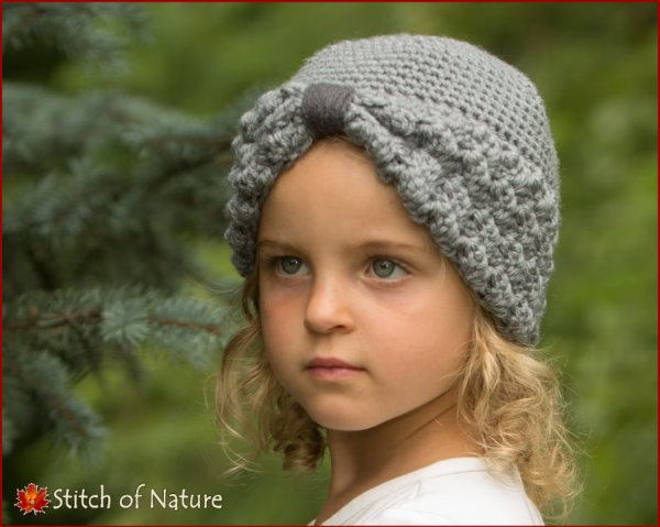 A little girl wearing a grey crochet turban hat.