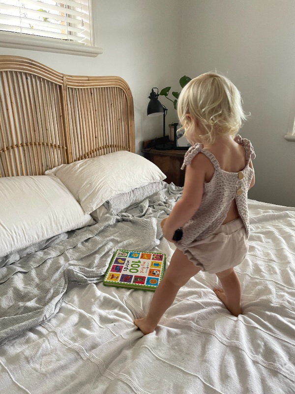 A toddler on  a bed, wearing a tunisian crochet baby top.