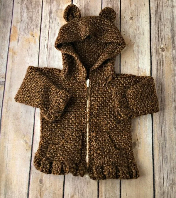 A brown crochet baby hoodie with a zipper and bear ears.