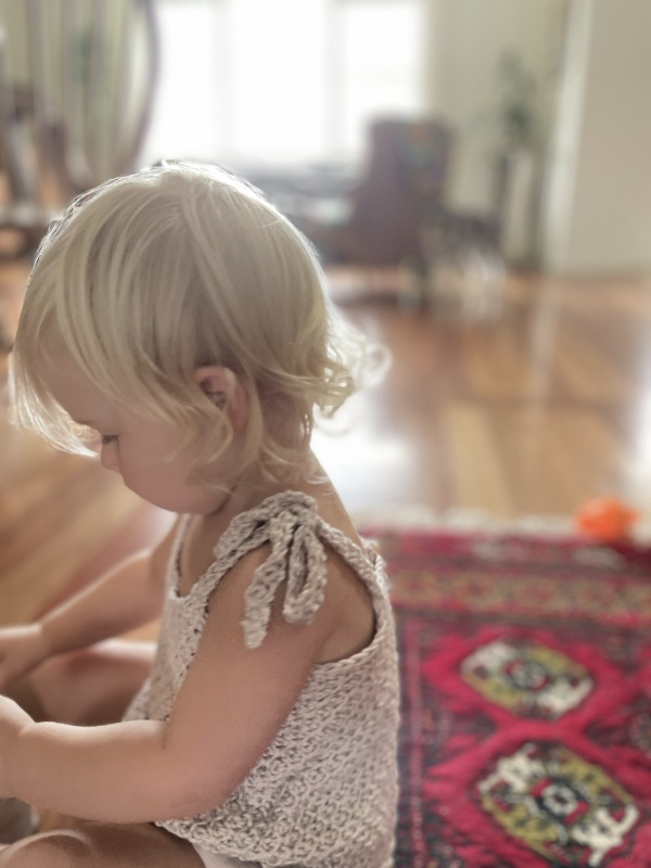 A closeup image of a toddler wearing a tunisian crochet baby top.