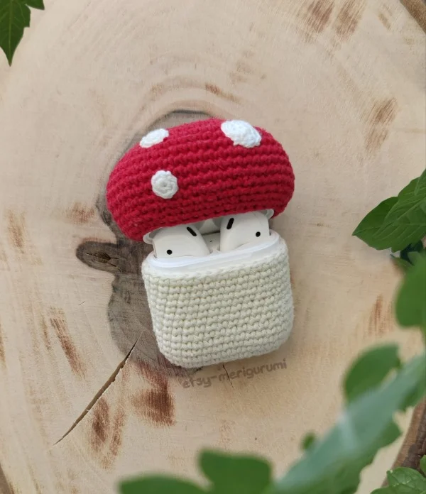 A red and white mushroom/toadstool themed crochet AirPods case.