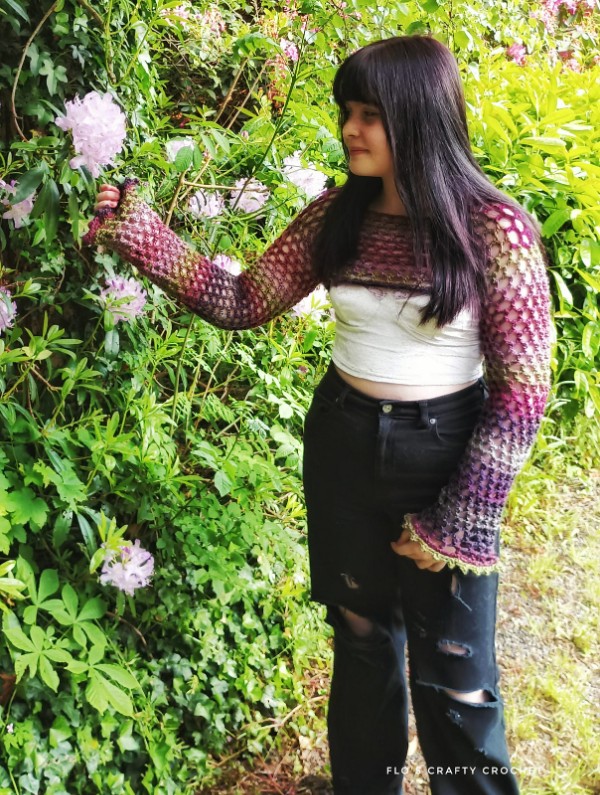 A woman in a garden wearing crochet sleeves top.