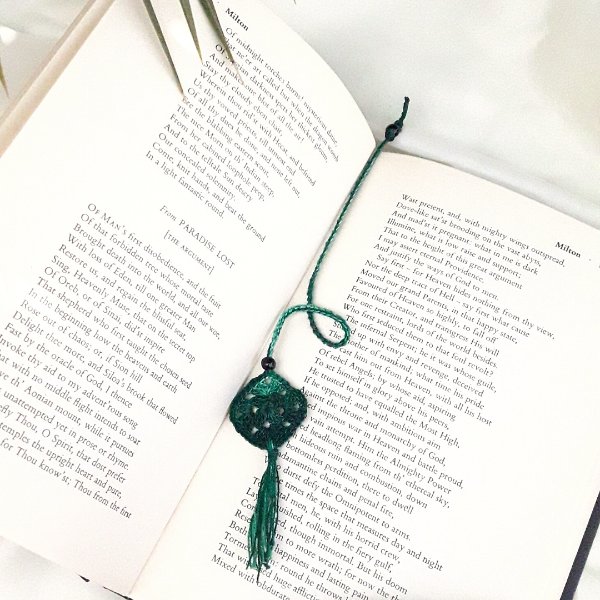 A small green granny square bookmark in an open book.