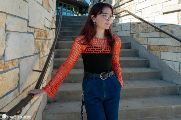 A person wearing a red mesh sleeves crochet top.
