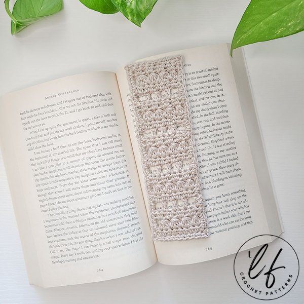 A linen coloured crochet lace bookmark in an open book.