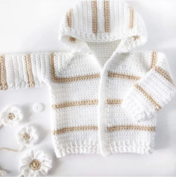 A white crochet baby hoodie with tan coloured stripes.