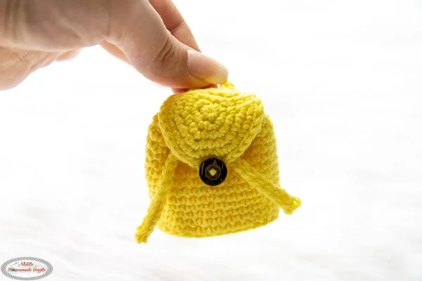 A yellow crocheted Airpods case in the shape of a mini-backpack.