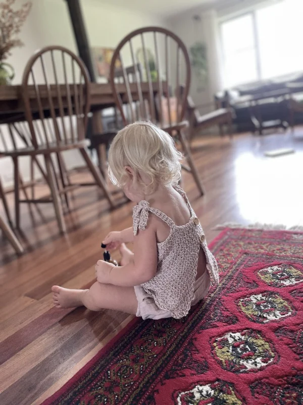 Side and back view of toddler wearing tunisian crochet thoneycomb stitch baby top.