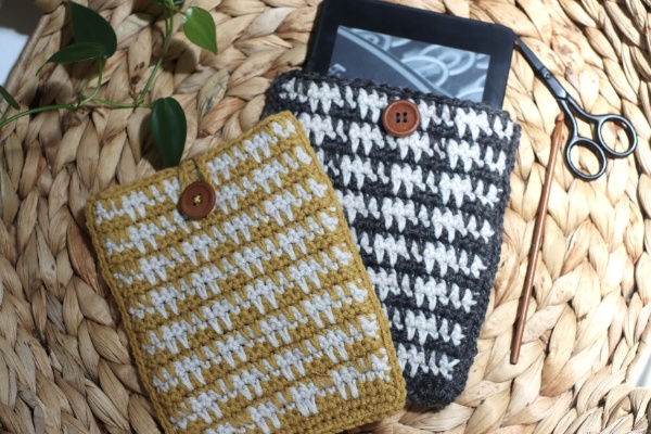Two houndstooth crochet kindle sleeves in a basket.