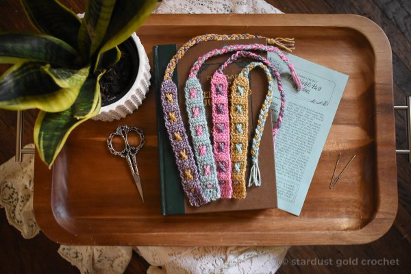 A pile of crochet bookmarks in a wooden tray.