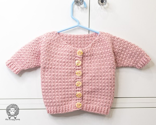 A tiny, pink crochet baby cardigan.