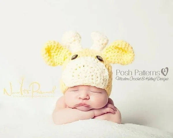 A newborn baby earing a giraffe-themed crochet animal hat.