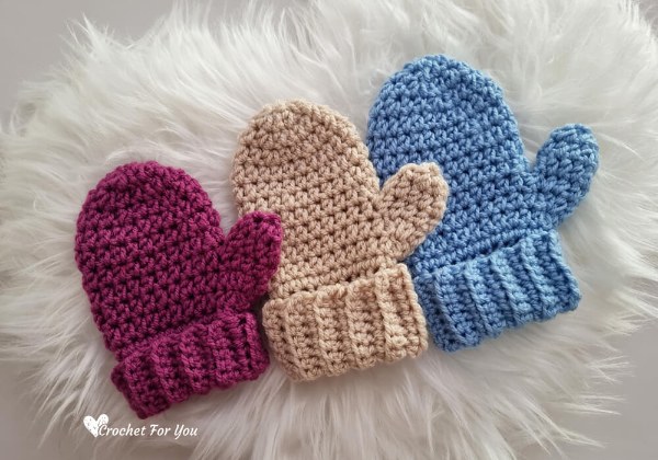 Three different colours and sizes of childrens crochet mittens.