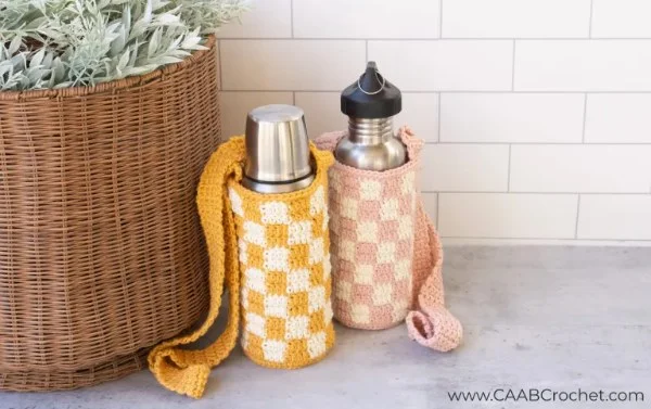 Two crochet water bottle holders with a checkerboard design.