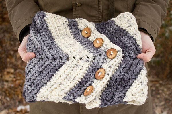 A flat lay image of a striped crochet button cowl with a chevron design.
