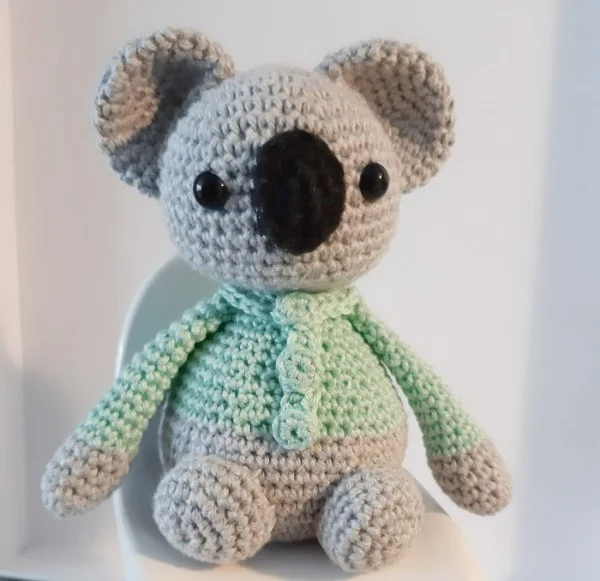 A crochet koala wearing a green sweater.