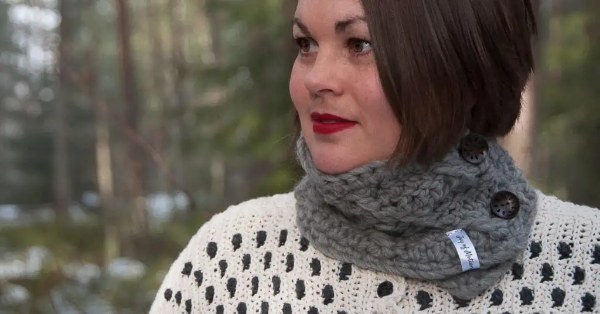 A close-up image of a woman wearing a grey crochet buttoned cowl.