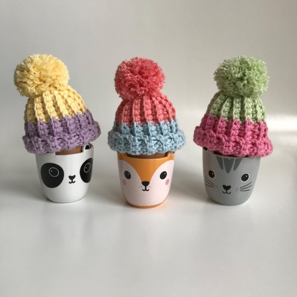 Three eggs with crochet hat cozies.