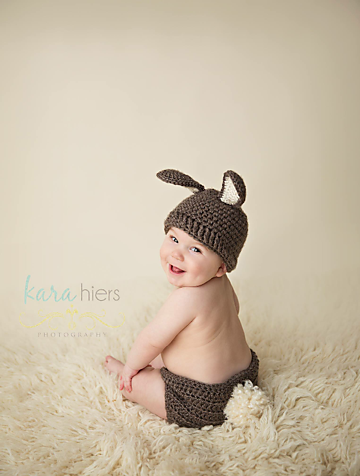 A baby with a crochet bunny hat and diaper covers.