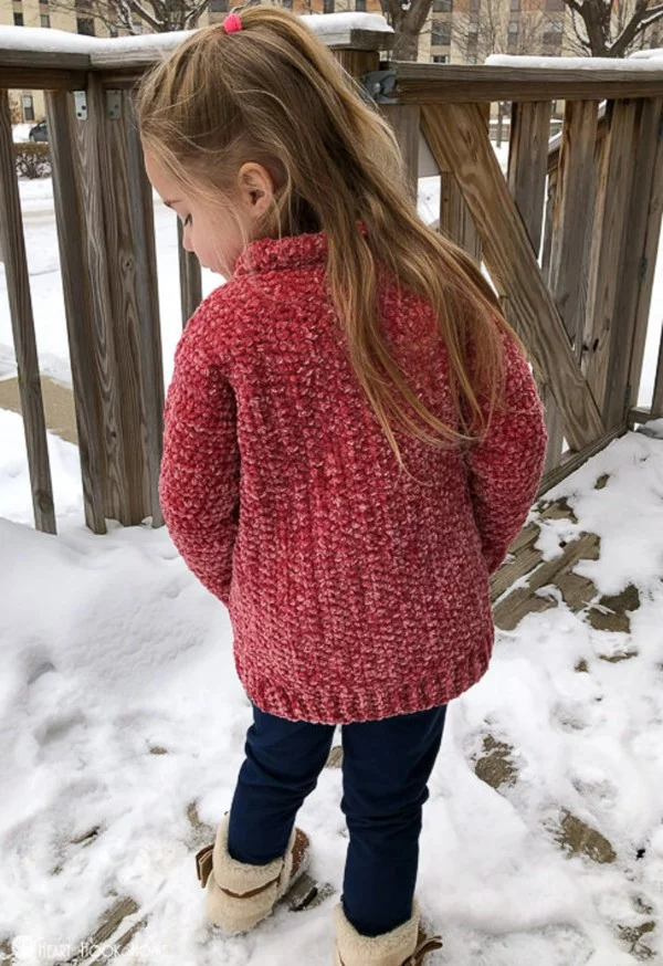 Back view of a child wearing a red crochet cardigan.