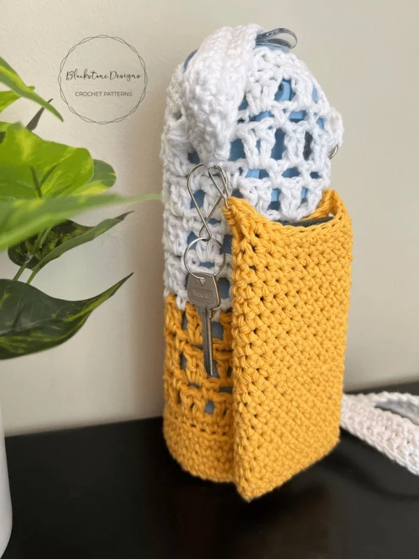 A yellow crochet water bottle holder with a pocket.