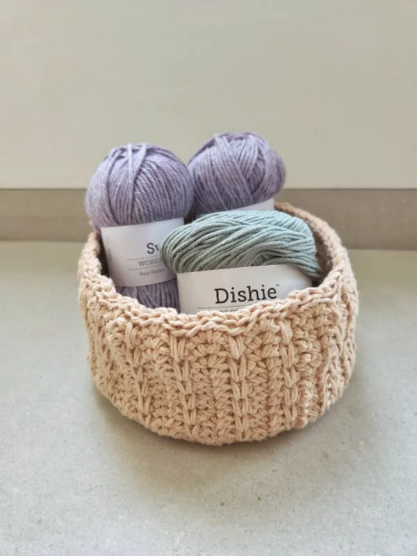 A crochet basket holding skeins of yarn.