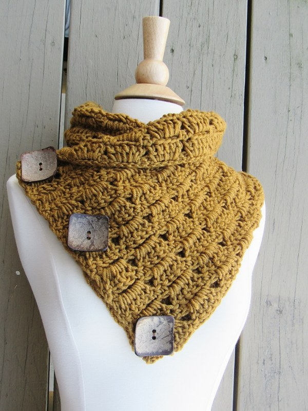 A mustard coloured crochet cowl with three large buttons.
