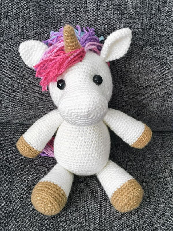 A crochet unicorn toy with pink hair.