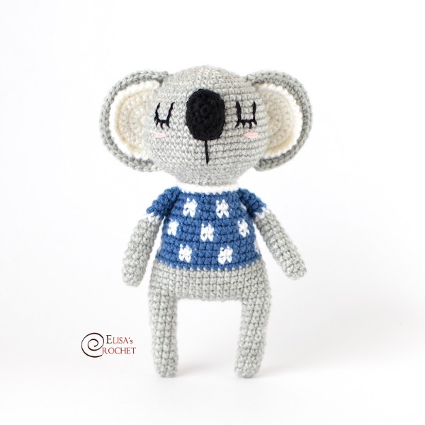 A crochet koala with a spotted blue shirt.