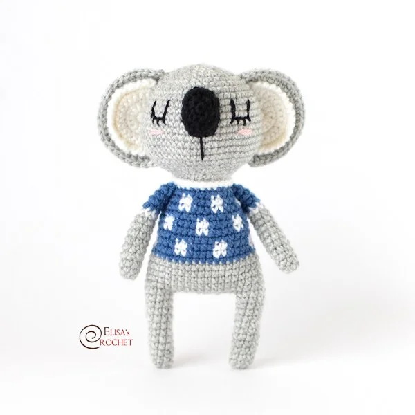 A crochet koala with a spotted blue shirt.