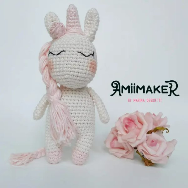 A pastel pink and white crochet unicorn amigurumi.