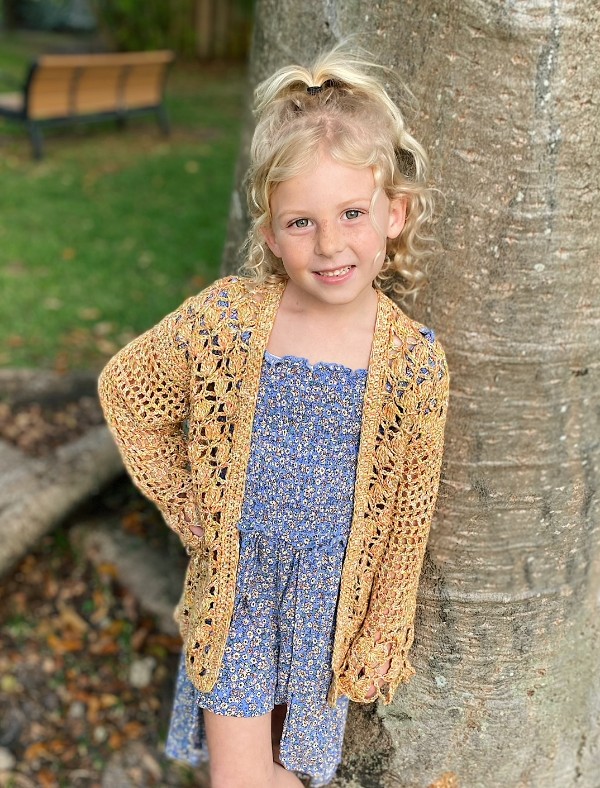 A child wearing a lacy, girl's crochet cardigan.