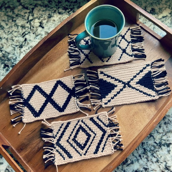 Four modern black and white crochet mug rugs.