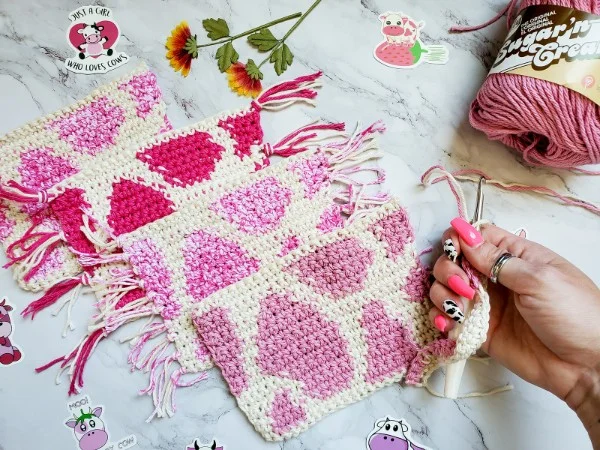 Four crochet mug rugs with a strawberry pink cow print.