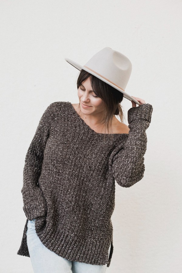 A woman wearing an oversized v-neck crochet sweater.