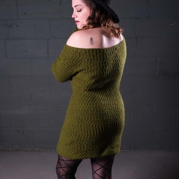Back view of a woman wearing an olive green crocheted sweater dress.