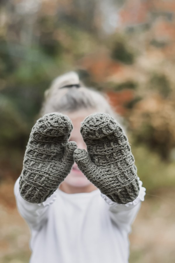 A child wearing a pair of crochet mittens.