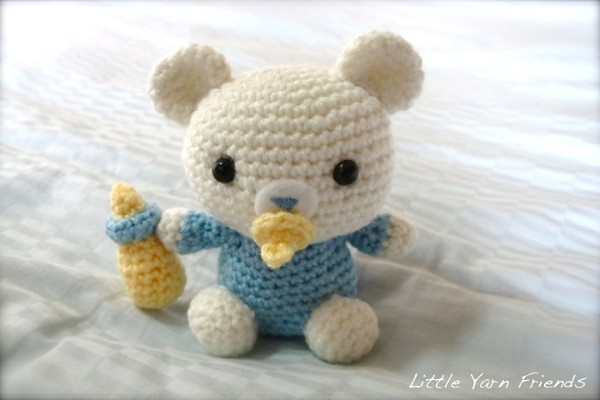 A crochet baby bear with a pacifier and a bottle.