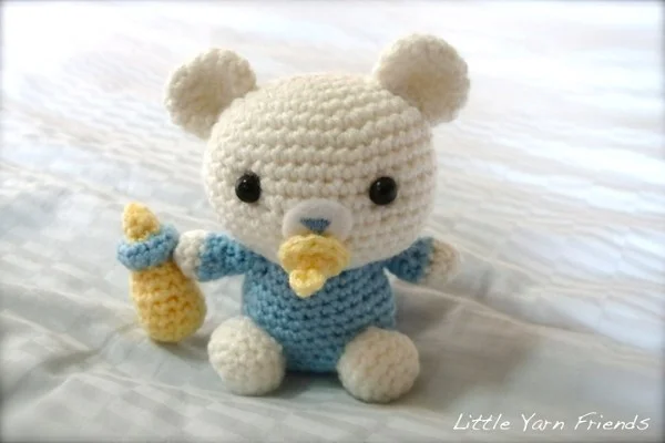 A crochet baby bear with a pacifier and a bottle.