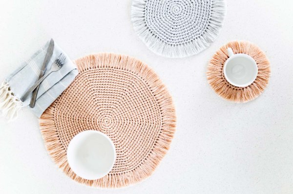 Three different-sized fringed crochet placemats.