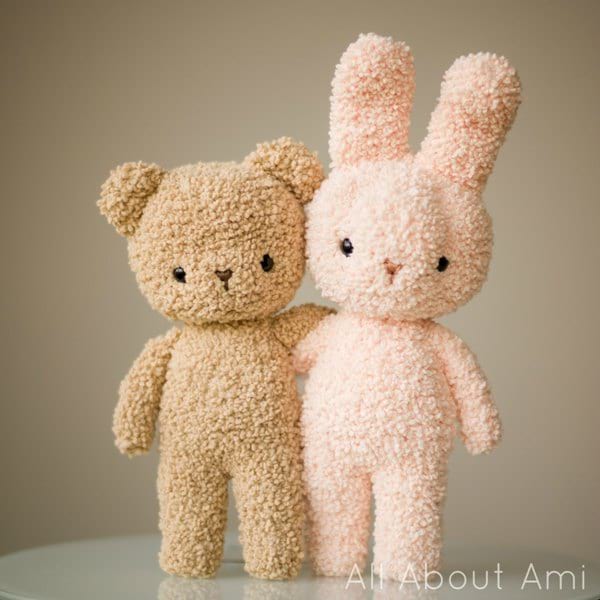 A teddy bear and a rabbit crocheted in boucle-style yarn.