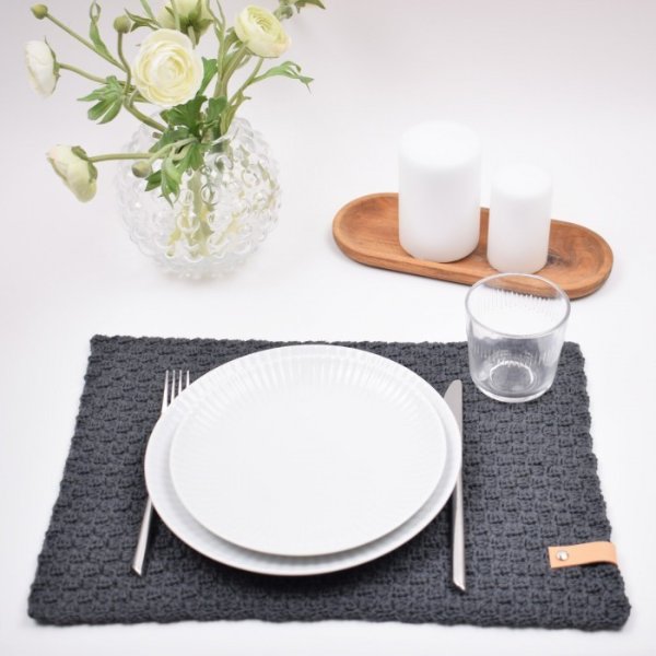 A dark grey crochet placemat table setting.