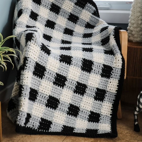 A black, white, and grey crochet gingham check blanket.