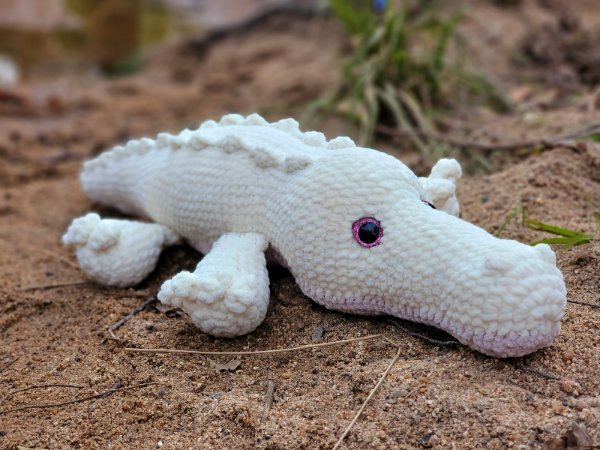 A white crochet alligator plushie.