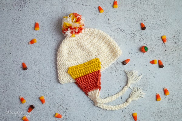 A crochet baby earflap hat with candy corn coloured stripes.